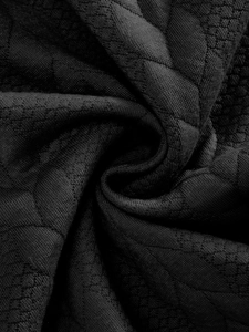 Vista macro de tejido de punto negro con textura de panal y patrones de jacquard