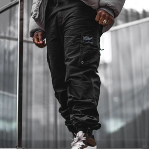Détail du pantalon cargo noir multi-poches avec chevilles resserrées et style urbain