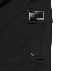 Vue détaillée du pantalon cargo noir montrant une poche latérale avec des étiquettes en tissu