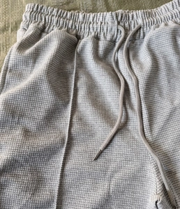 Detail view of grey waffle knit fabric with elastic waistband and drawstring tips