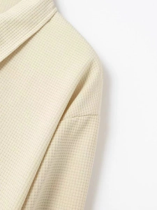 Dettaglio della trama a nido d'ape beige e delle cuciture sulle spalle della giacca
