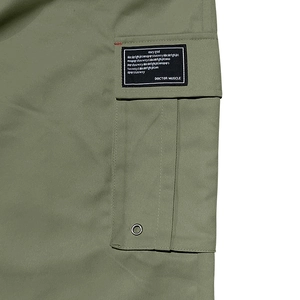 Détail du pantalon cargo vert armée avec grande poche à rabat et étiquette textile brodée