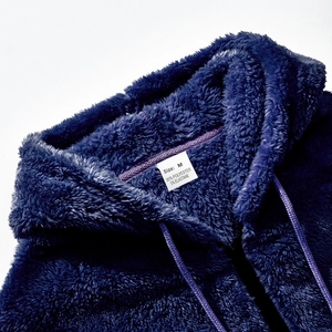 Detailaufnahme des Kragens der dunkelblauen Kapuzenjacke mit dem Pflegeetikett in Größe M
