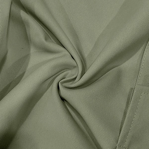 Gros plan du tissu sergé vert olive montrant les coutures détaillées du pantalon cargo