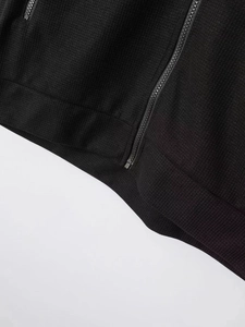 Détail du tissu gaufré et fermeture éclair en métal sur une veste noire pour homme
