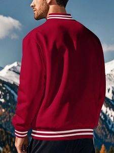 Men's deep red baseball jacket with white striped ribbing against a snowy mountain backdrop