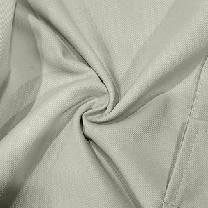 Détail macro du tissu en sergé gris-vert clair et couture industrielle sur pantalon cargo