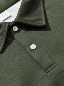 Macro shot of dark green polo shirt collar with white button and textured pique fabric