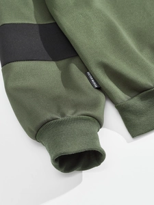 Detailed macro view of heavy green cotton sweatshirt with ribbed cuffs and side brand label