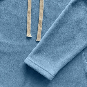 Close-up of blue polar fleece fabric detail with white drawstrings on hooded sweatshirt