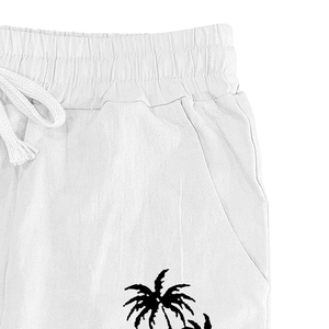 Close-up of white linen pants featuring elastic drawstring waist and black coconut tree print