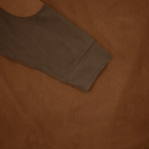 Detailed macro view of dark brown corduroy fabric texture and ribbed cuff design