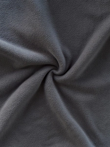 Close-up of soft dark grey polar fleece fabric texture with warm fluffy pile detail