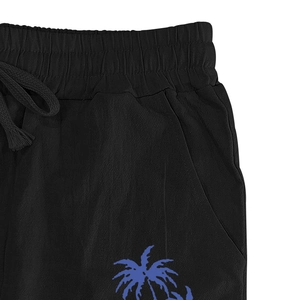 Detail of men's linen pants featuring elastic drawstring waist and palm tree print