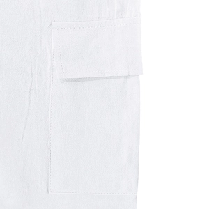 Détail du pantalon cargo en lin blanc montrant la texture respirante et la poche à rabat