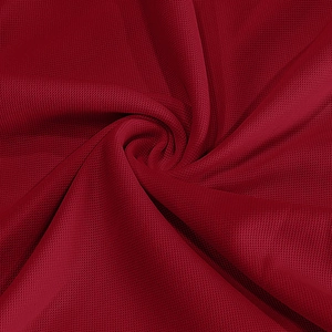 Detailed macro view of dark red breathable honeycomb mesh fabric on a men's polo shirt