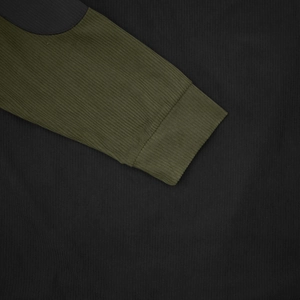 Detail of ribbed corduroy texture and raglan sleeve stitching on olive green sweatshirt