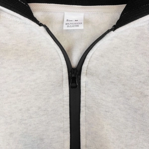 Detail of light grey zip-up hoodie featuring M size label and polyester blend fabric