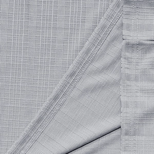 Macro shot of gray breathable fabric showing square texture and neat overlock stitching