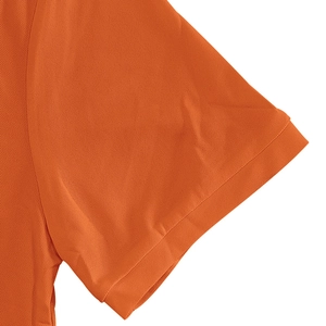 Detailed close-up of orange polo shirt sleeve with breathable pique mesh fabric and ribbed cuff
