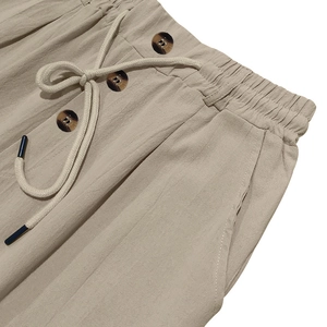 Dettaglio dei pantaloni beige in cotone e lino con coulisse e bottoni decorativi