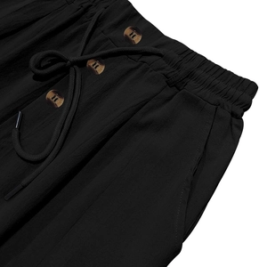 Dettaglio dei pantaloni in lino nero da uomo con elastico in vita, coulisse e bottoni ambra