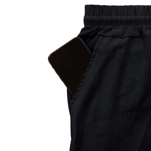 Détail de la taille élastique et poche profonde sur pantalon en lin noir avec téléphone