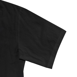 Detalle de las mangas cortas y textura del tejido de una camisa casual negra con capucha