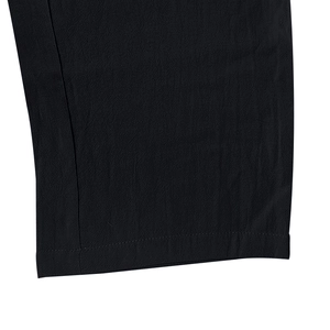 Gros plan sur l'ourlet à double couture et le lin texturé d'un pantalon décontracté noir