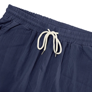 Detail of navy blue linen shorts featuring elastic waist and cotton drawstring with metal tips