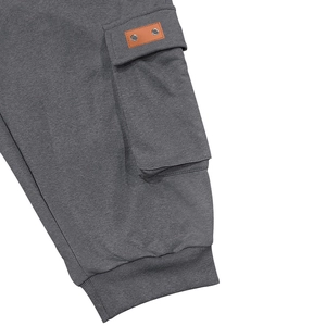 Detail of dark gray cargo short pocket featuring leather patch and metal rivets