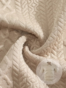 Detalle del polo de punto beige con textura jacquard geométrica y tejido de alta gama
