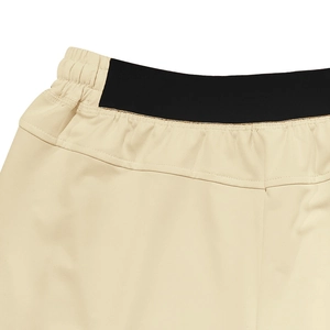 Detail view of beige sport shorts with elastic waist and black stretch patchwork fabric