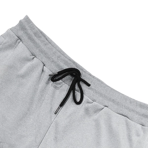 Detail of light gray joggers featuring an elastic ribbed waistband and black drawstrings