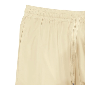Detail of beige drawstring waistband with metal tips and side pockets on sports shorts