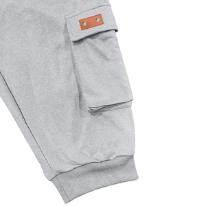 Detail of light gray cargo shorts with ribbed cuffs and side pocket with leather tag