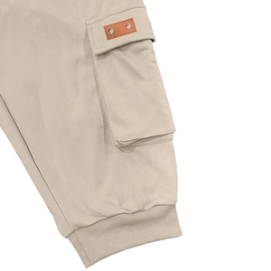 Detail view of khaki cargo shorts featuring a side pocket with leather tag and ribbed cuffs