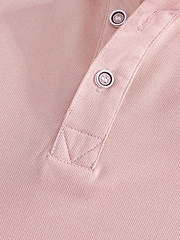 Macro detail of pink piqué polo shirt placket with round buttons and reinforced stitching