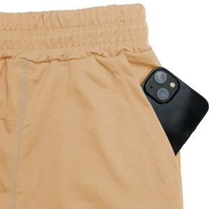 Detail of apricot sports shorts featuring wide elastic waistband and deep side pocket