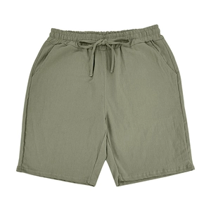 Detail of olive green linen shorts featuring elastic waistband and adjustable drawstring