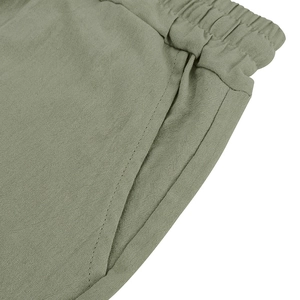 Detail of light olive linen shorts featuring elastic waistband and reinforced side pockets
