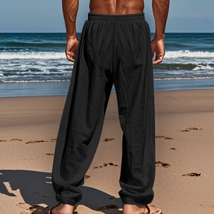 Pantaloni larghi in lino nero da uomo con coulisse elastica in vita su una spiaggia assolata