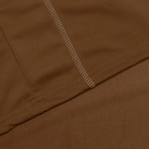 Close-up of brown sports suit showing reinforced flatlock stitching on knit fabric