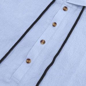Detail view of light blue linen fabric texture with amber buttons and black piping