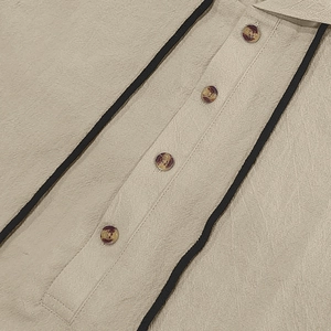 Detail of linen shirt with amber buttons and black decorative trim on beige fabric