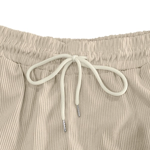 Detail of beige corduroy shorts featuring an elastic drawstring waist with metal tips