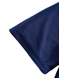 Détail macro de la double couture sur le poignet d'un polo bleu marine à séchage rapide