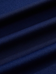 Gros plan du tissu polo bleu marine montrant la texture respirante en maille nid d'abeille