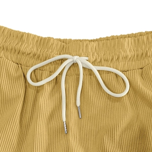 Close-up of yellow corduroy shorts with elastic waistband and white drawstring