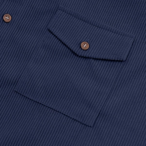 Dettaglio macro della camicia di velluto blu navy con taschino e bottoni in legno
